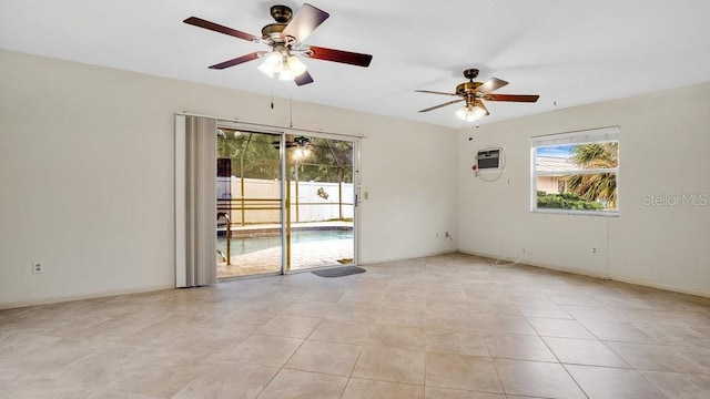 spare room featuring ceiling fan, light tile patterned flooring, and a wall unit AC