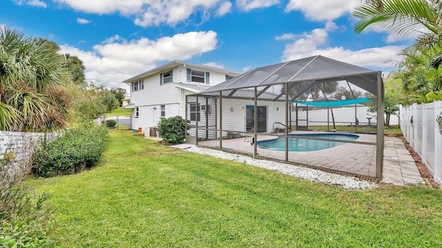 rear view of property featuring a lanai, a fenced in pool, a patio area, and a yard