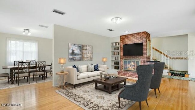 living room featuring built in features, a fireplace, and hardwood / wood-style flooring