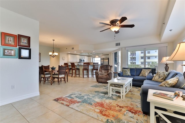 tiled living room with ceiling fan with notable chandelier