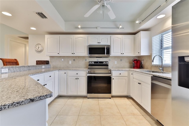 kitchen with light stone countertops, sink, white cabinets, and appliances with stainless steel finishes