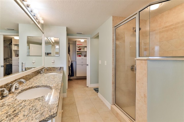 bathroom featuring tile patterned flooring, vanity, a shower with shower door, and a textured ceiling