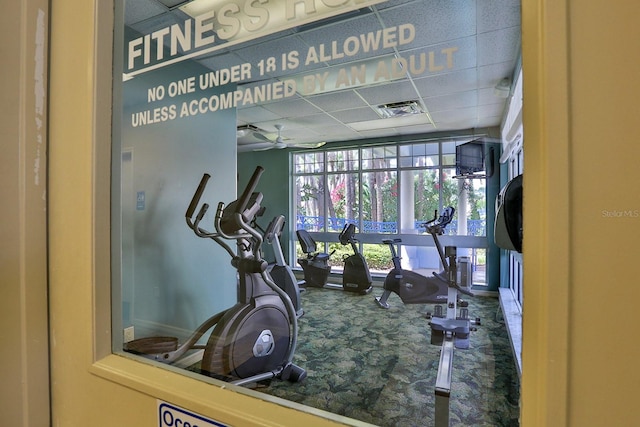 workout area with a paneled ceiling, carpet floors, and ceiling fan