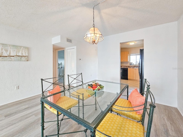 3606 S Peninsula Dr Unit 404, Port Orange, FL 32127 - dining room featuring light wood-style flooring, a chandelier, and a textured ceiling