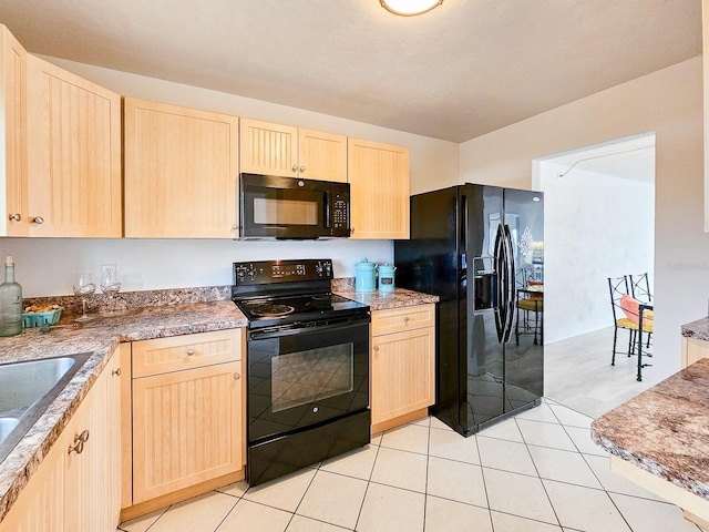 kitchen featuring light brown cabinetry, light tile patterned floors, black appliances, and sink