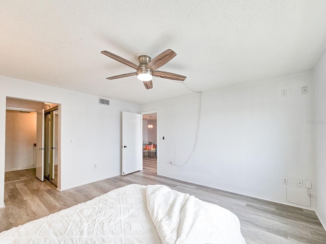 bedroom featuring a textured ceiling, light hardwood / wood-style floors, and ceiling fan