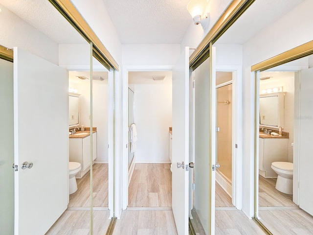 bathroom with vanity, wood-type flooring, a textured ceiling, and toilet