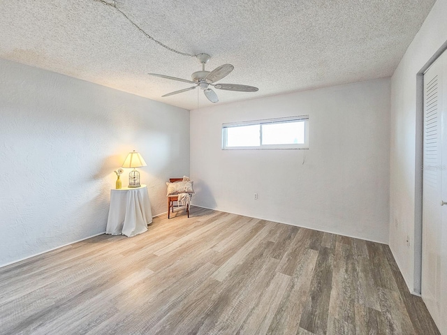 unfurnished room with ceiling fan, wood-type flooring, and a textured ceiling