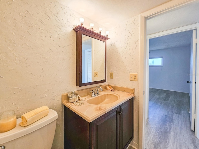 bathroom featuring vanity, wood-type flooring, a textured ceiling, and toilet