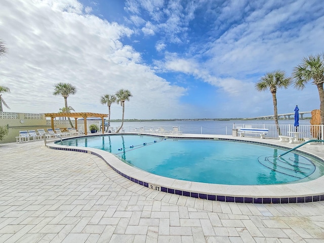 view of pool with a patio area, a water view, and a pergola