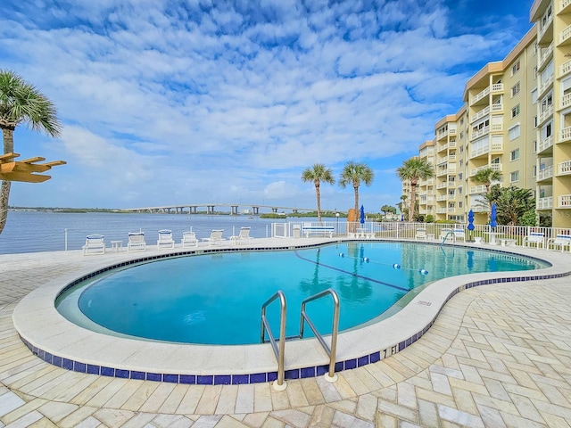 view of pool with a water view and a patio