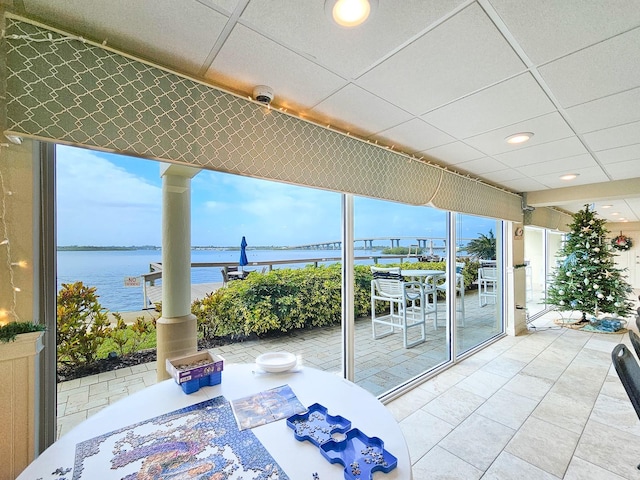 sunroom / solarium with a paneled ceiling and a water view