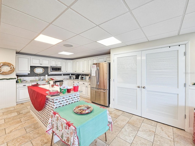 3606 S Peninsula Dr Unit 404, Port Orange, FL 32127 - kitchen with stainless steel appliances, a paneled ceiling, light countertops, white cabinets, and a center island
