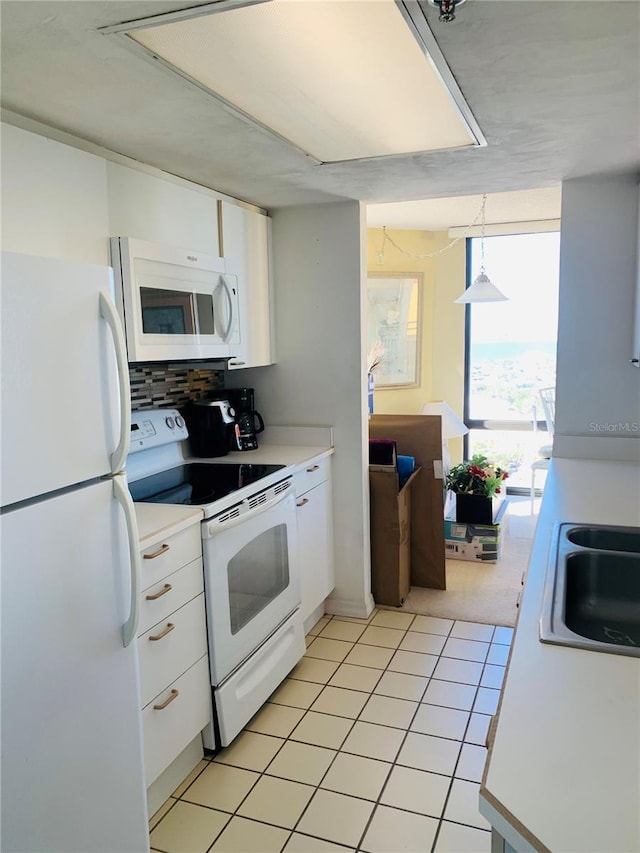 kitchen with white cabinetry, sink, hanging light fixtures, backsplash, and white appliances