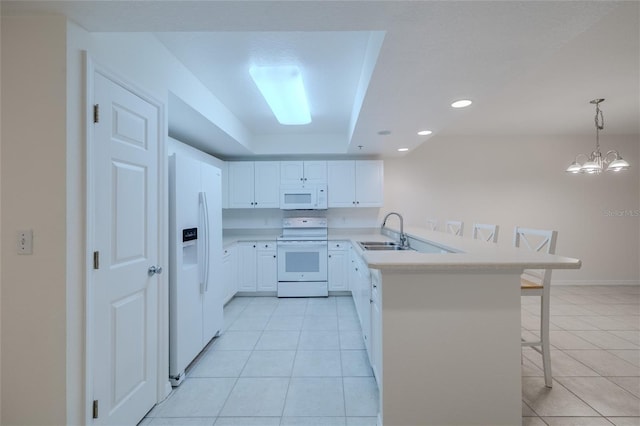 kitchen with pendant lighting, white appliances, white cabinets, kitchen peninsula, and a breakfast bar area