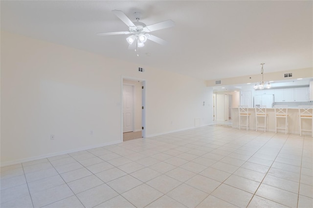 tiled spare room featuring ceiling fan with notable chandelier