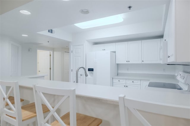 kitchen with sink, backsplash, white appliances, a breakfast bar area, and white cabinets