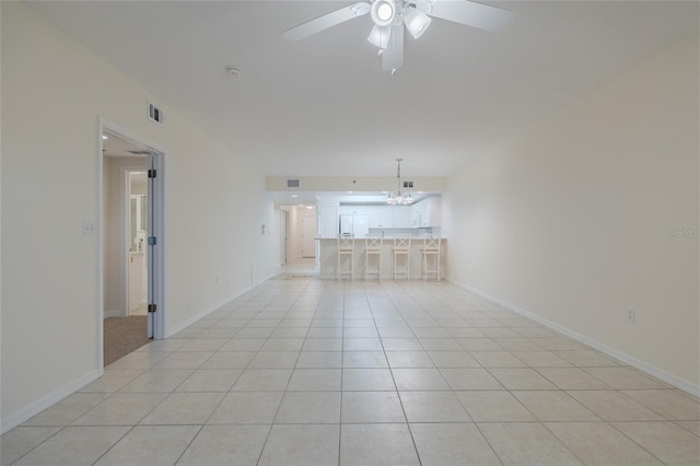 unfurnished living room featuring ceiling fan with notable chandelier and light tile patterned flooring