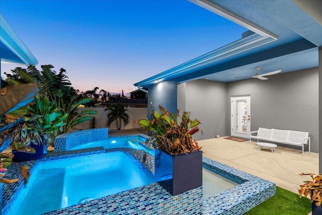 pool at dusk with an in ground hot tub, pool water feature, and a patio area