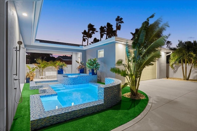 pool at dusk featuring an in ground hot tub