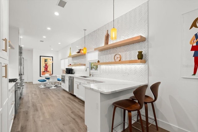 kitchen featuring pendant lighting, white cabinets, sink, kitchen peninsula, and stainless steel appliances