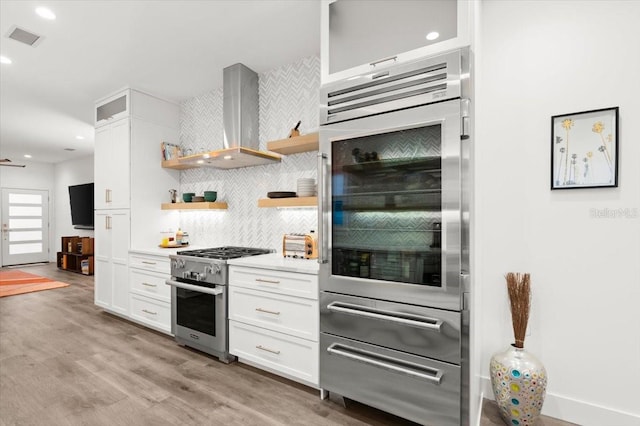 kitchen with white cabinetry, stainless steel range, and wall chimney exhaust hood