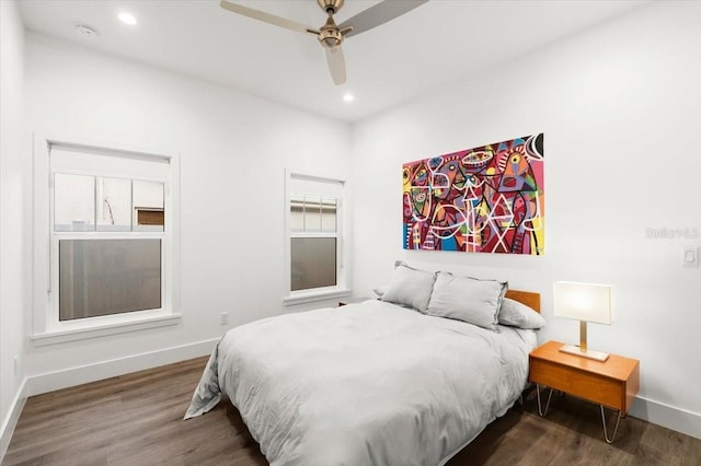 bedroom featuring ceiling fan, dark wood-type flooring, and multiple windows