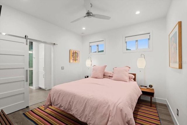 bedroom with a barn door, ceiling fan, hardwood / wood-style floors, and ensuite bathroom