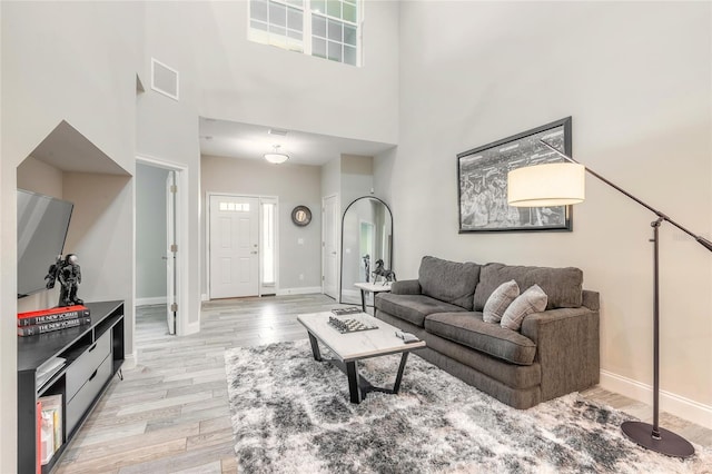 living room with light hardwood / wood-style floors and a towering ceiling