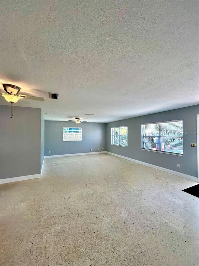 unfurnished room with ceiling fan, plenty of natural light, and a textured ceiling