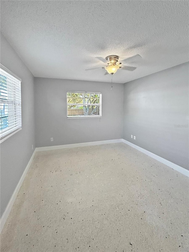 empty room with ceiling fan, a textured ceiling, and a wealth of natural light