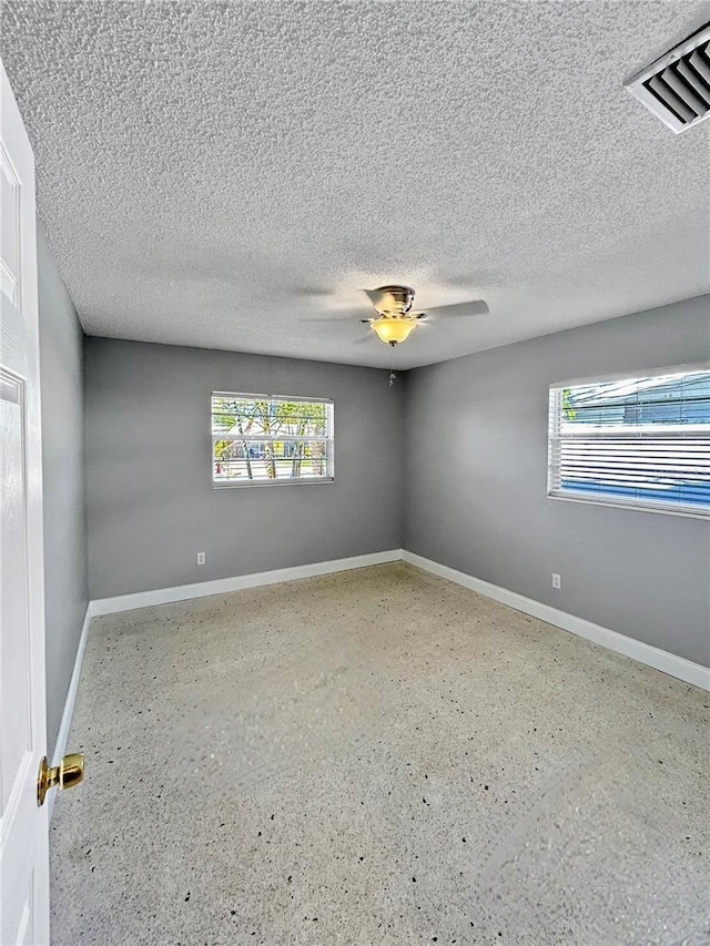 unfurnished room with a textured ceiling and a wealth of natural light