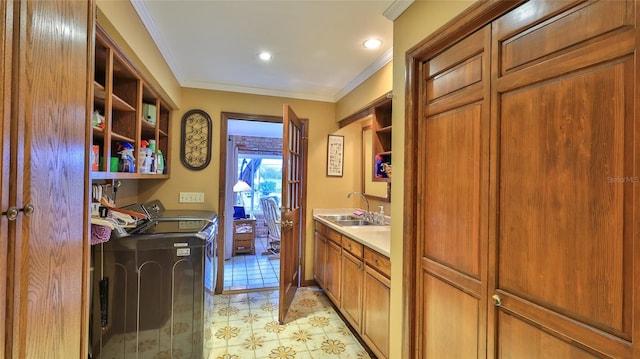 clothes washing area featuring crown molding, cabinets, separate washer and dryer, and sink