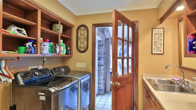 clothes washing area featuring sink, cabinets, crown molding, washer and clothes dryer, and light tile patterned floors