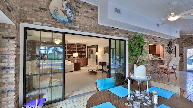 interior space with tile patterned flooring, ceiling fan, and brick wall