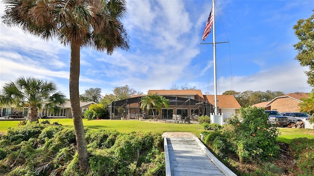 rear view of house with a yard and a lanai