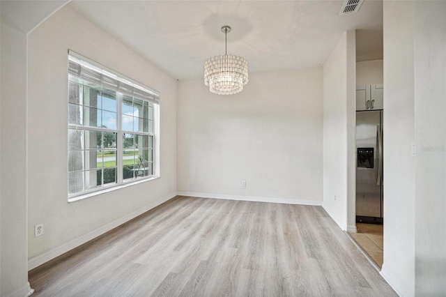 unfurnished room with a chandelier and light wood-type flooring