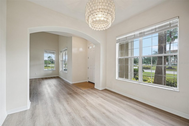 empty room featuring a chandelier and light hardwood / wood-style flooring