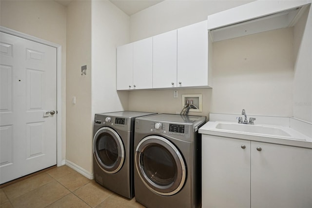 clothes washing area with washer and clothes dryer, cabinets, light tile patterned floors, and sink