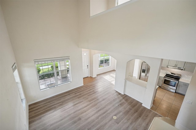 unfurnished living room with light hardwood / wood-style floors and a towering ceiling