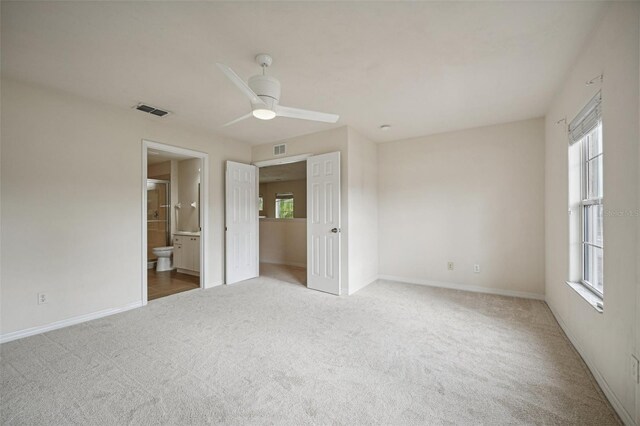 unfurnished bedroom with carpet flooring, ensuite bath, and ceiling fan