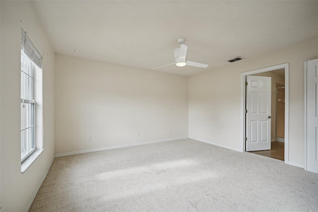 spare room featuring dark colored carpet, ceiling fan, and a healthy amount of sunlight