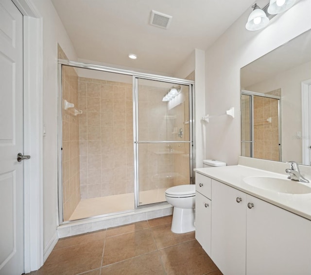 bathroom with tile patterned floors, a shower with door, vanity, and toilet