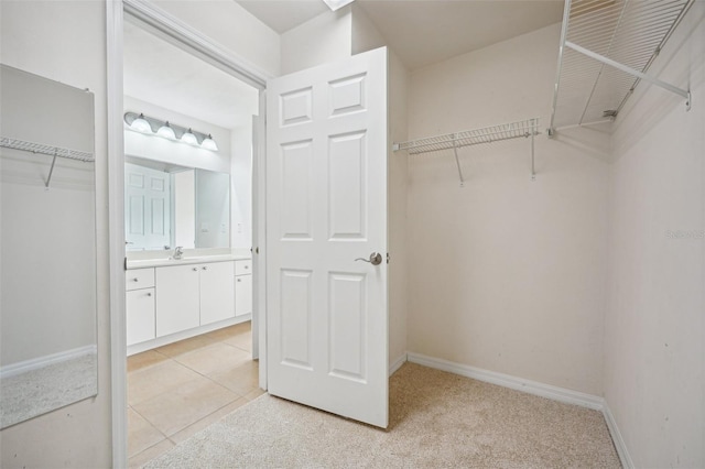 walk in closet featuring light carpet and sink