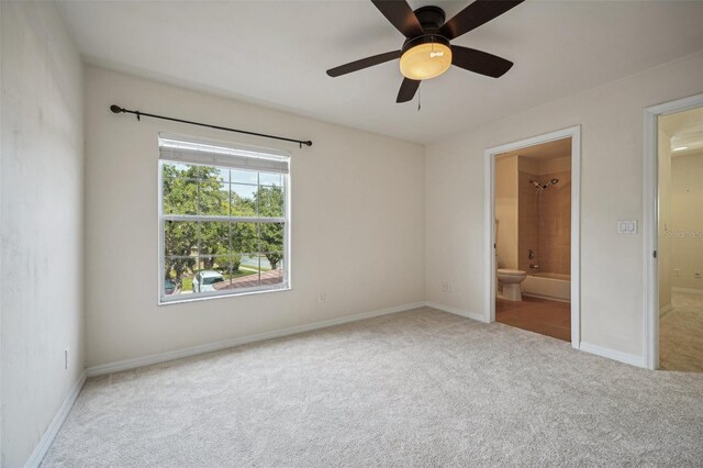 unfurnished bedroom featuring ceiling fan, light colored carpet, and ensuite bath