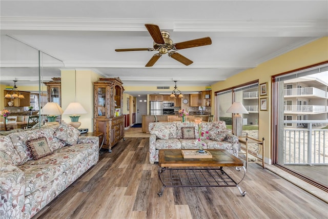 living room with beamed ceiling, wood-type flooring, ornamental molding, and ceiling fan