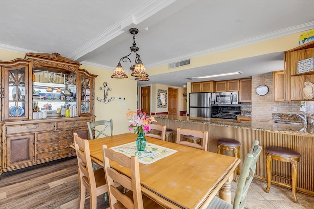 dining area with sink, crown molding, and wood-type flooring