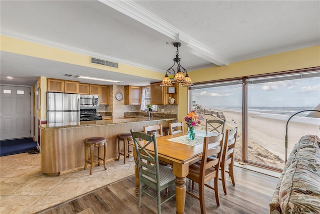 dining room featuring crown molding, a water view, beam ceiling, and light hardwood / wood-style floors