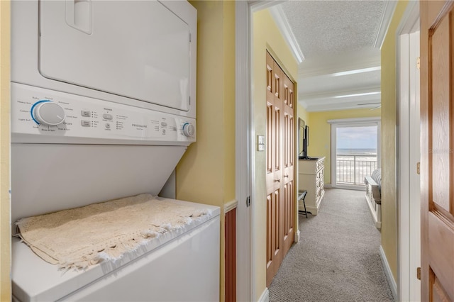 washroom featuring stacked washer / dryer, crown molding, light carpet, and a textured ceiling