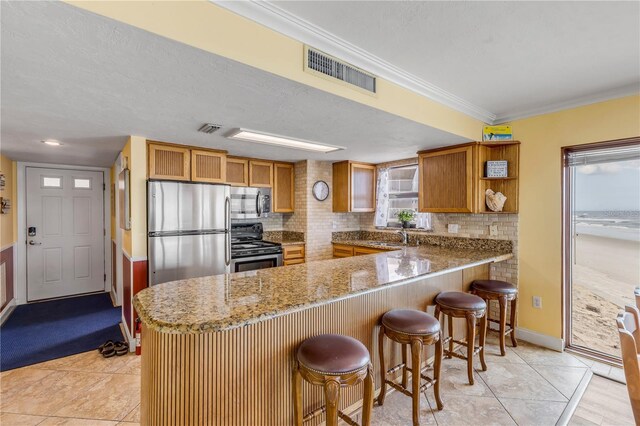 4811 Saxon Dr Unit C102, New Smyrna Beach, FL 32169 - kitchen with brown cabinets, a sink, stainless steel appliances, a peninsula, and visible vents